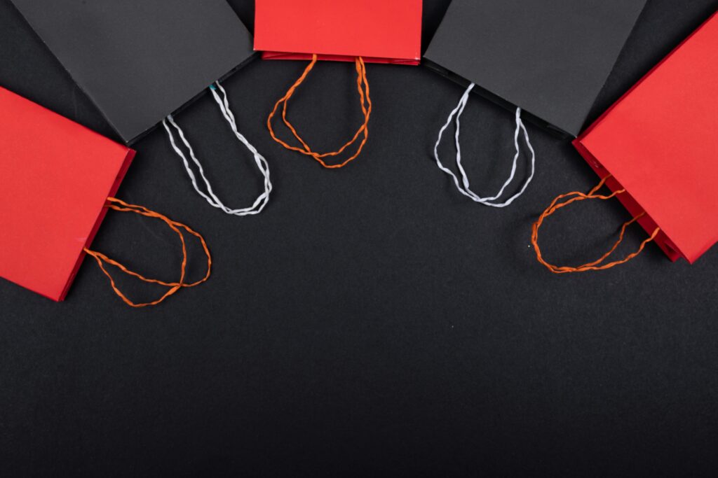 Flat lay of red and black paper bags on a black background with copy space.